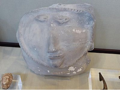 A grey stone pot with a face, from Roman times